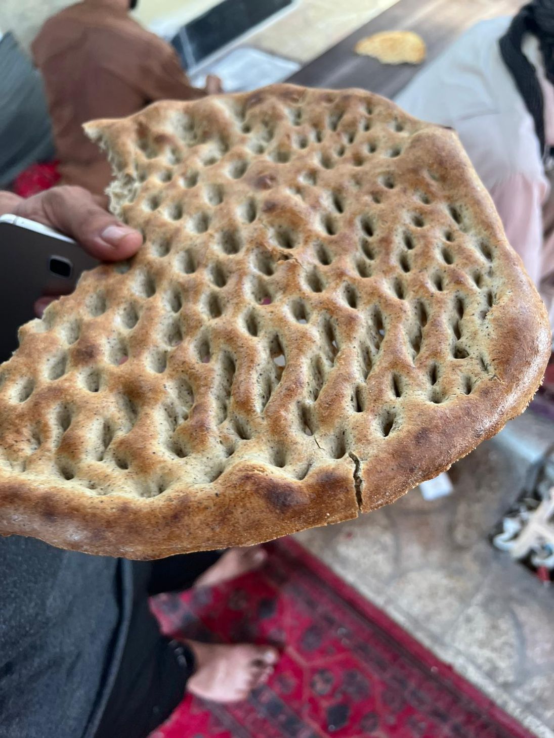 Baked brown flat bread with many holes throughout similar to Naan bread.