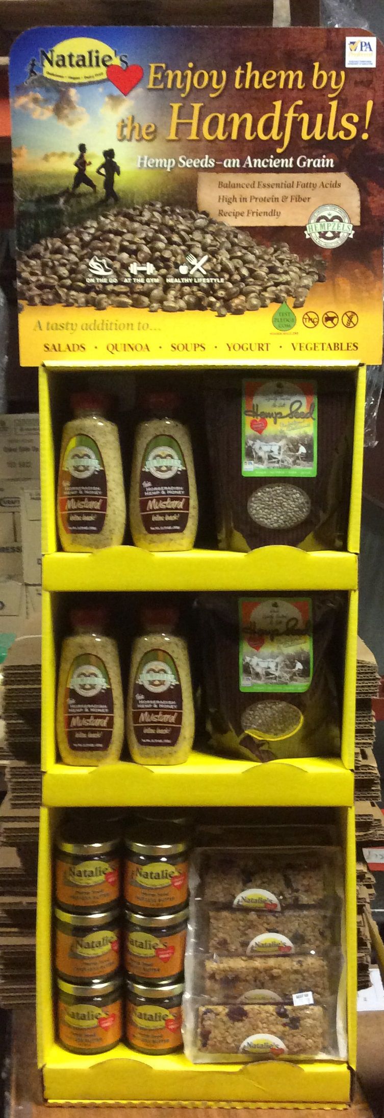 Bright yellow display with multi-color display, on shelves are mustard, hemp seed, butter and granola bars.